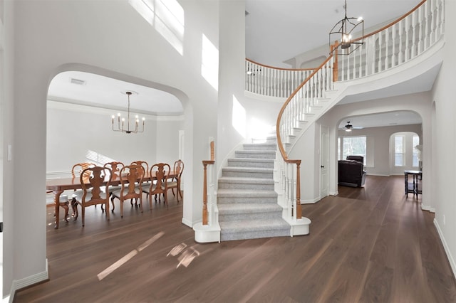 entryway featuring dark hardwood / wood-style flooring, ceiling fan with notable chandelier, a high ceiling, and ornamental molding