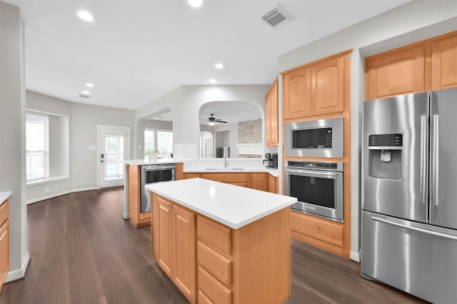 kitchen with kitchen peninsula, sink, stainless steel appliances, and a kitchen island