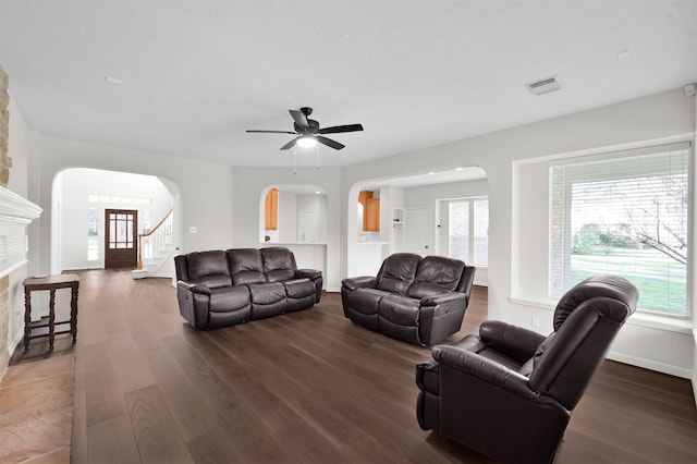 living room featuring dark wood-type flooring, ceiling fan, and a fireplace