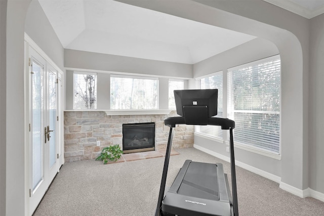 exercise room featuring a stone fireplace and carpet flooring