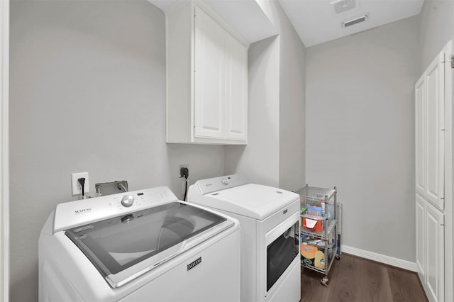 clothes washing area with washer and dryer, cabinets, and dark wood-type flooring