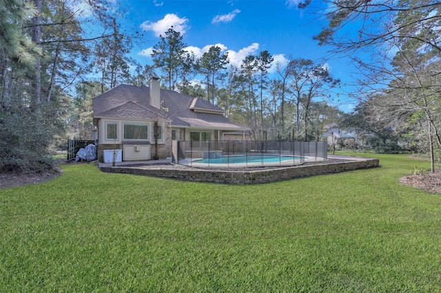 back of house featuring a fenced in pool and a yard