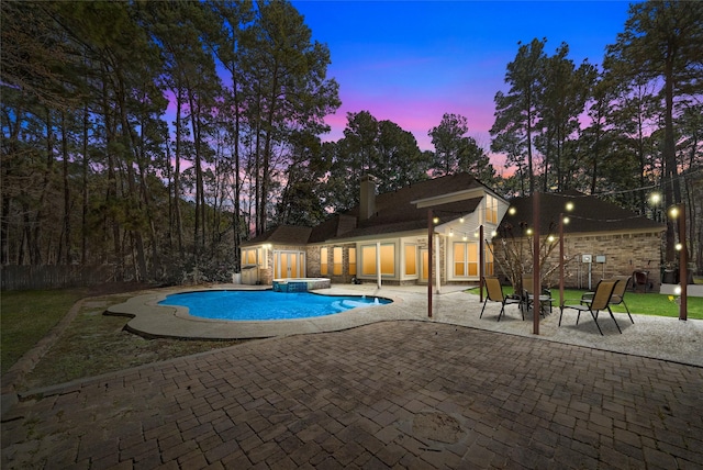 pool at dusk with a patio area