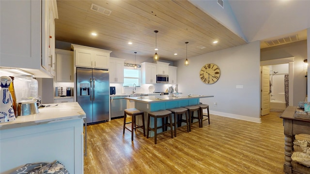 kitchen with a kitchen island, pendant lighting, sink, appliances with stainless steel finishes, and white cabinets