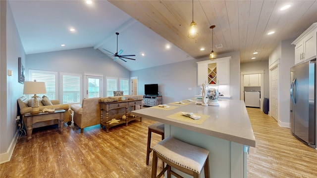 kitchen featuring decorative light fixtures, white cabinetry, a breakfast bar area, stainless steel fridge, and wooden ceiling