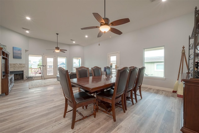 dining room featuring ceiling fan, a fireplace, and light hardwood / wood-style flooring