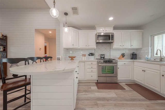 kitchen with sink, white cabinetry, appliances with stainless steel finishes, and a breakfast bar area