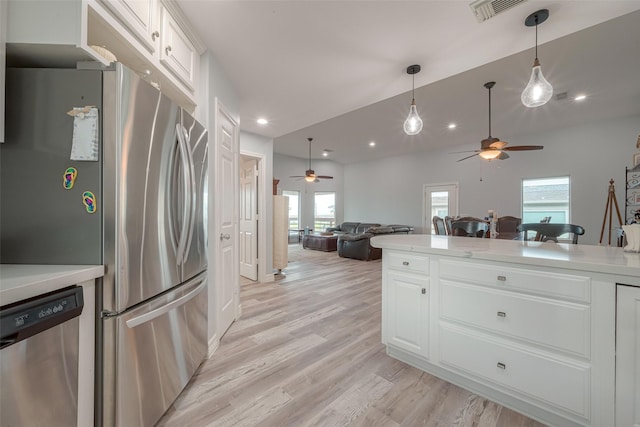 kitchen with light hardwood / wood-style floors, white cabinetry, appliances with stainless steel finishes, and lofted ceiling