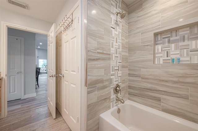 bathroom with tiled shower / bath combo and hardwood / wood-style flooring