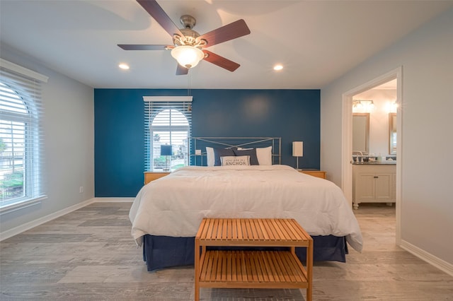 bedroom with ceiling fan, ensuite bath, and light wood-type flooring