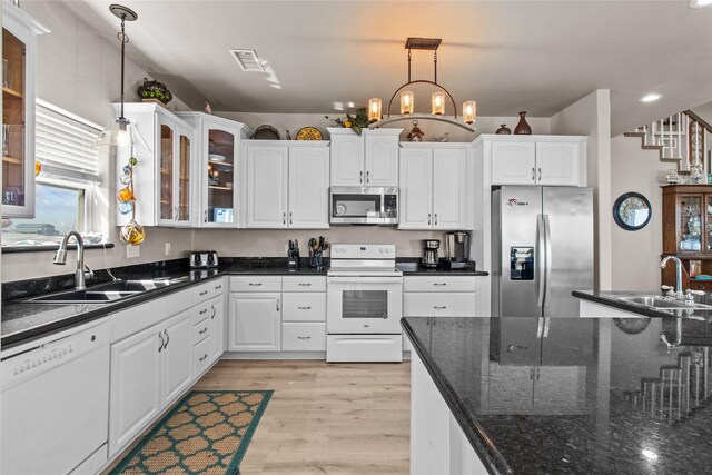 kitchen featuring pendant lighting, appliances with stainless steel finishes, glass insert cabinets, white cabinetry, and a sink