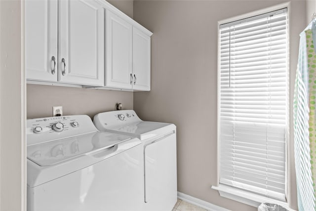 clothes washing area featuring light tile patterned flooring, cabinet space, baseboards, and separate washer and dryer