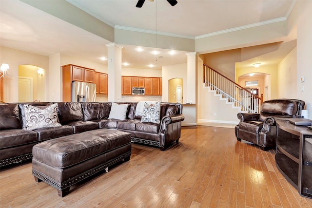 living room with light hardwood / wood-style floors, decorative columns, ornamental molding, and ceiling fan