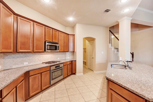 kitchen featuring decorative backsplash, light stone countertops, stainless steel appliances, and light tile patterned flooring