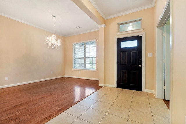 foyer entrance with light tile patterned floors, a chandelier, and ornamental molding