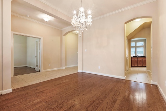 spare room featuring light hardwood / wood-style floors, ornamental molding, and a chandelier