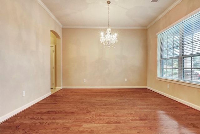 spare room with a notable chandelier, crown molding, and hardwood / wood-style floors