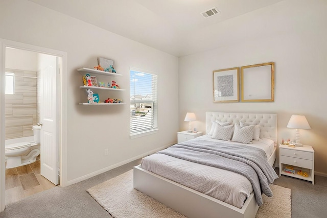 bedroom with ensuite bathroom and light hardwood / wood-style flooring