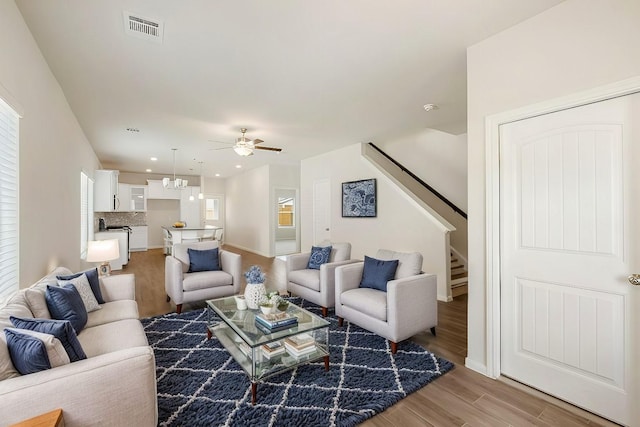 living room with wood-type flooring and ceiling fan with notable chandelier