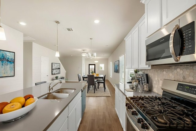 kitchen featuring dark hardwood / wood-style floors, sink, white cabinetry, hanging light fixtures, and appliances with stainless steel finishes