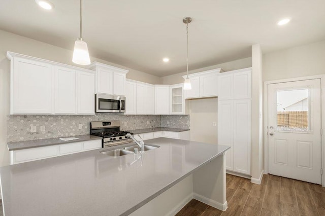 kitchen with white cabinetry, appliances with stainless steel finishes, light wood-type flooring, hanging light fixtures, and sink