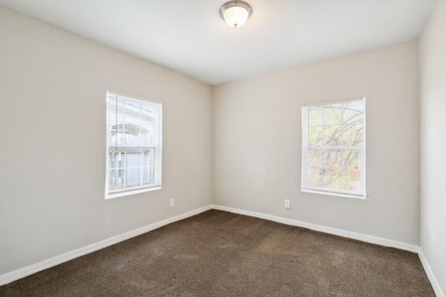 spare room featuring dark colored carpet