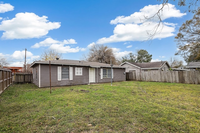 back of house with a yard and a fenced backyard