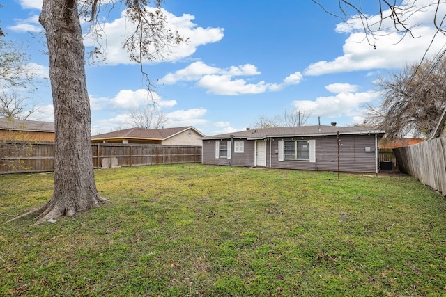 rear view of property with a yard and a fenced backyard