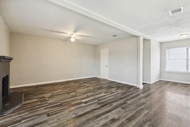 unfurnished living room featuring a textured ceiling, ceiling fan, a fireplace, and dark hardwood / wood-style floors