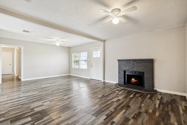 unfurnished living room featuring ceiling fan, dark hardwood / wood-style floors, a fireplace, and a textured ceiling