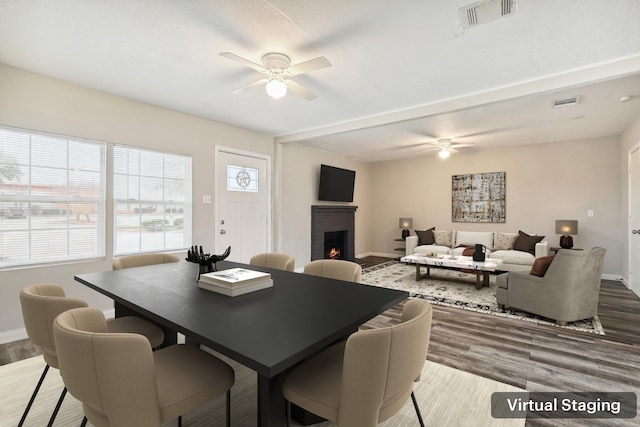 dining area featuring hardwood / wood-style flooring, a brick fireplace, and ceiling fan