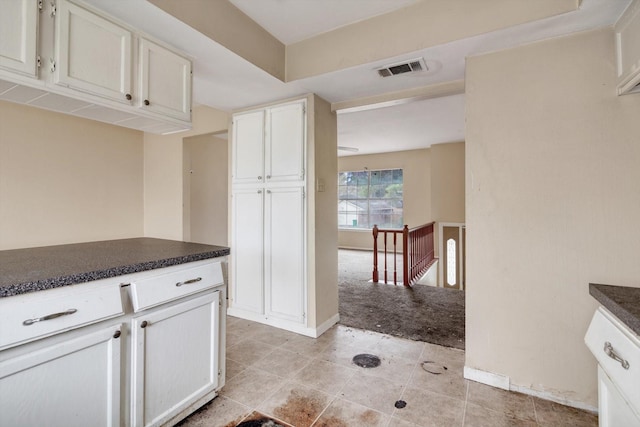 kitchen with light carpet and white cabinetry