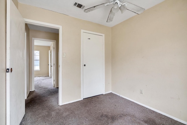 unfurnished bedroom with ceiling fan and dark colored carpet