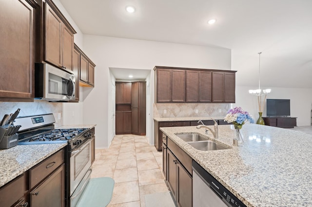 kitchen with light stone countertops, pendant lighting, stainless steel appliances, an inviting chandelier, and sink