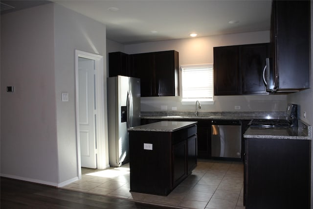 kitchen with light tile patterned flooring, stainless steel appliances, a center island, and sink