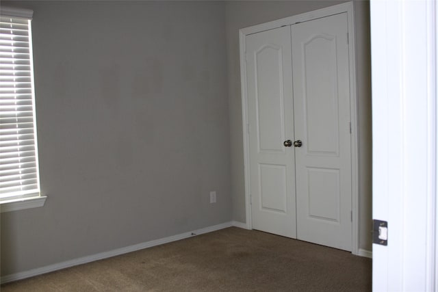 unfurnished bedroom with a closet and dark colored carpet