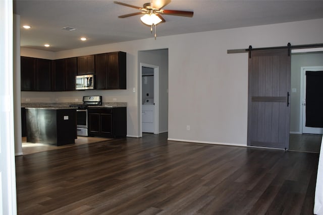 kitchen with dark hardwood / wood-style flooring, ceiling fan, dark brown cabinetry, stainless steel appliances, and a barn door