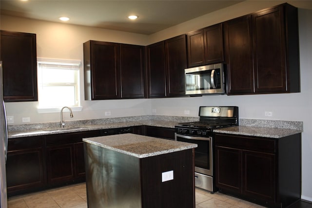 kitchen featuring dark brown cabinetry, sink, a kitchen island, stainless steel appliances, and light stone countertops