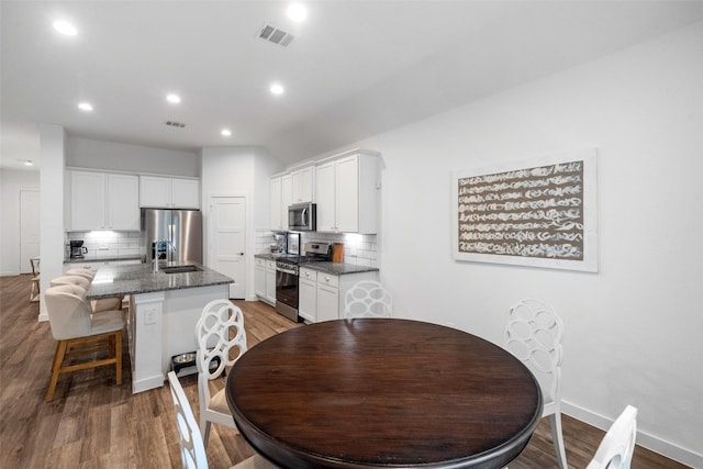 dining space with sink and wood-type flooring