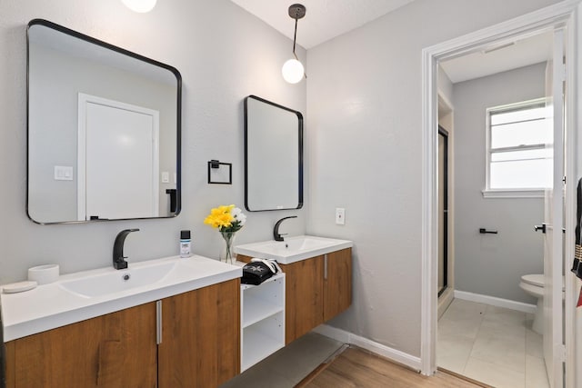 bathroom with a shower with door, vanity, and toilet