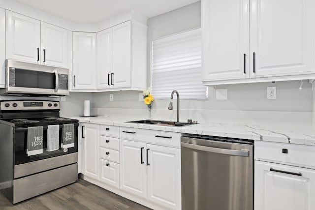 kitchen featuring sink, white cabinetry, appliances with stainless steel finishes, dark hardwood / wood-style flooring, and light stone countertops