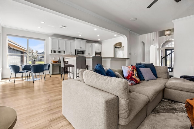 living room with crown molding, light hardwood / wood-style floors, and ceiling fan