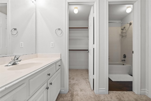 bathroom featuring a textured ceiling, tiled shower / bath, and vanity