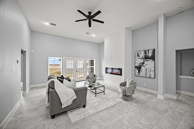 living room with a high ceiling, ceiling fan, and french doors