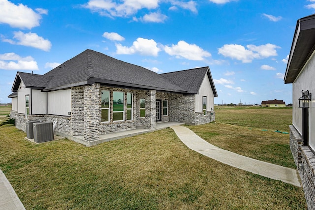 exterior space with a front yard, central air condition unit, and a patio