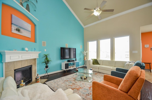 living room featuring crown molding, hardwood / wood-style floors, a tile fireplace, high vaulted ceiling, and ceiling fan