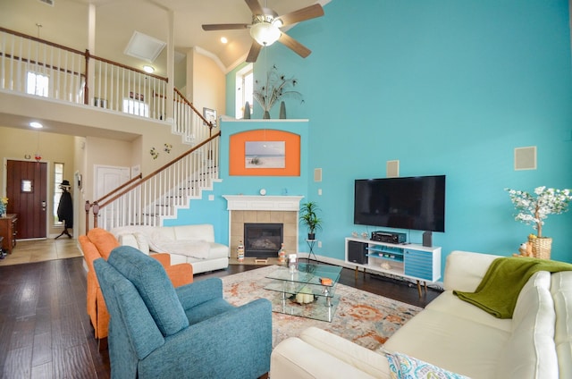 living room featuring wood-type flooring, a fireplace, a high ceiling, and ceiling fan