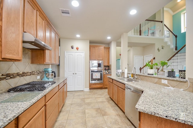 kitchen featuring light stone countertops, appliances with stainless steel finishes, sink, backsplash, and light tile patterned floors