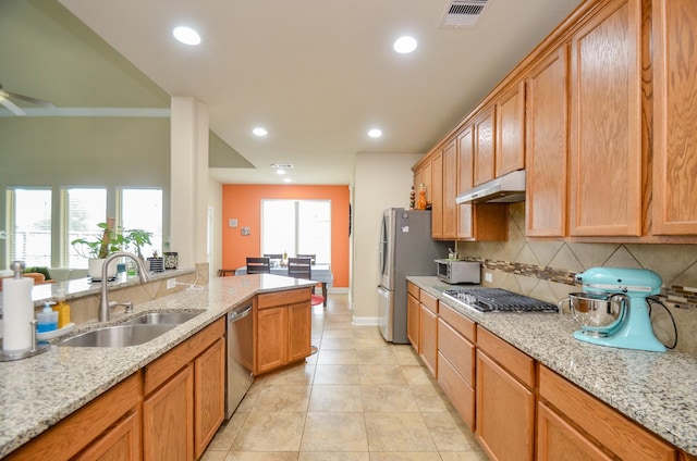 kitchen featuring appliances with stainless steel finishes, sink, tasteful backsplash, light tile patterned floors, and light stone countertops