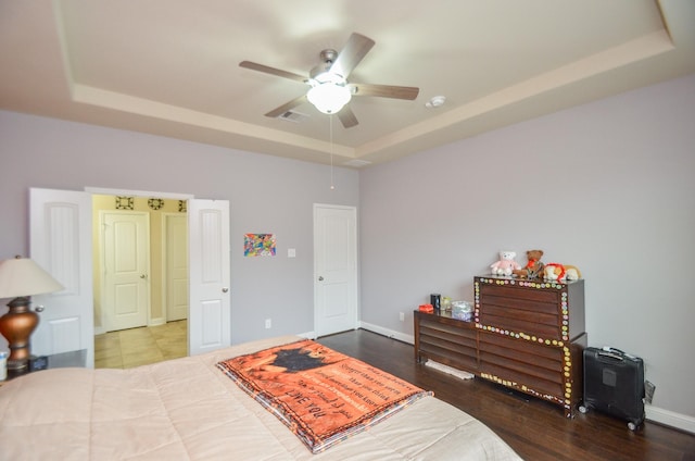 bedroom with ceiling fan, wood-type flooring, and a raised ceiling